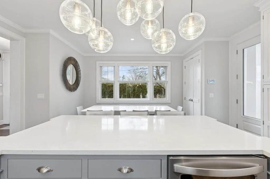 Kitchen with decorative light fixtures, gray cabinets, a kitchen island, and crown molding Kitchen with decorative light fixtures, gray cabinets, a kitchen island, and crown molding