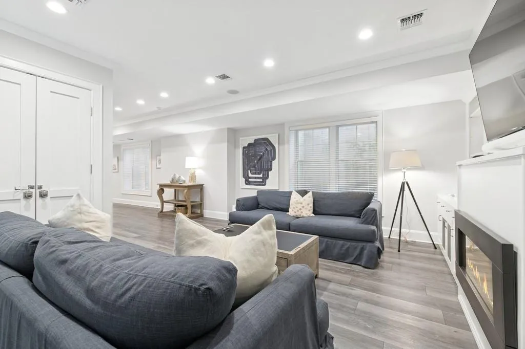 Living room featuring visible vents, crown molding, recessed lighting, light wood-style floors, and a glass covered fireplace Living room featuring visible vents, crown molding, recessed lighting, light wood-style floors, and a glass covered fireplace