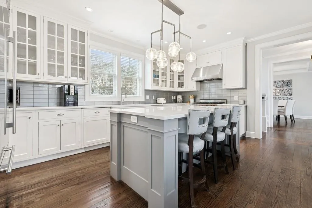 Kitchen featuring under cabinet range hood, dark wood finished floors, a center island, and light countertops Kitchen featuring under cabinet range hood, dark wood finished floors, a center island, and light countertops