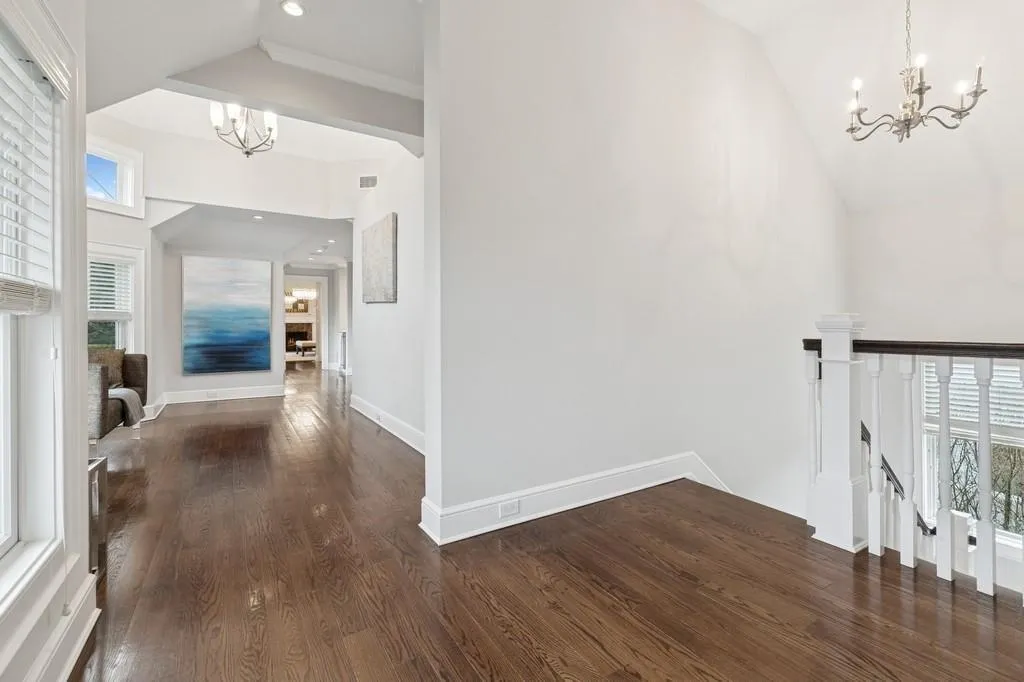 Hall featuring an upstairs landing, dark wood finished floors, baseboards, and an inviting chandelier Hall featuring an upstairs landing, dark wood finished floors, baseboards, and an inviting chandelier