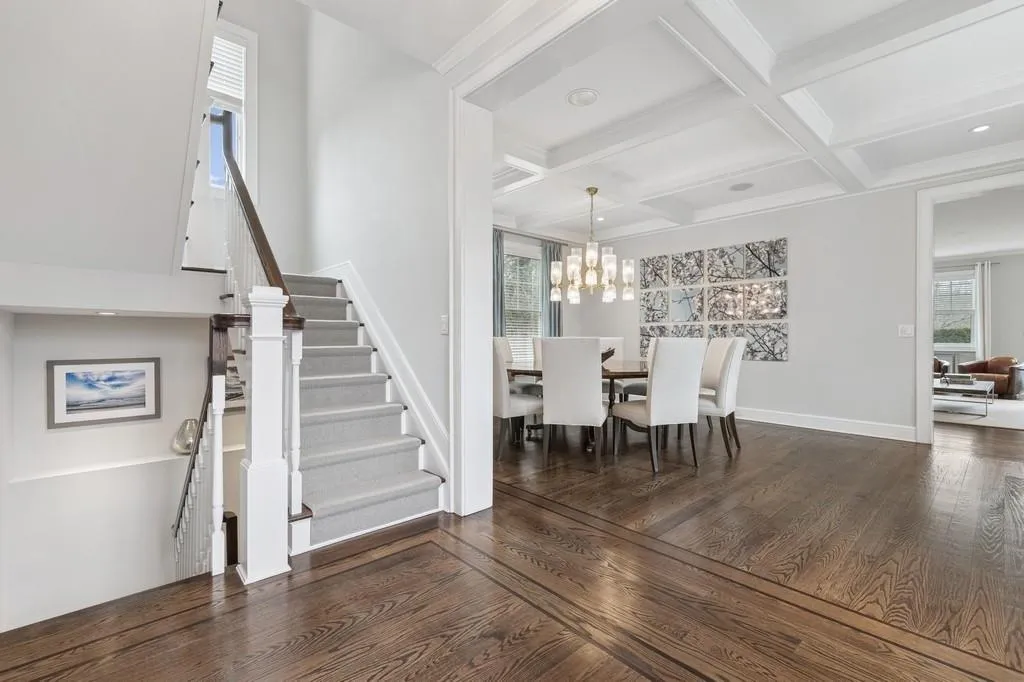 Dining area featuring hardwood / wood-style floors, baseboards, coffered ceiling, beam ceiling, and stairs Dining area featuring hardwood / wood-style floors, baseboards, coffered ceiling, beam ceiling, and stairs