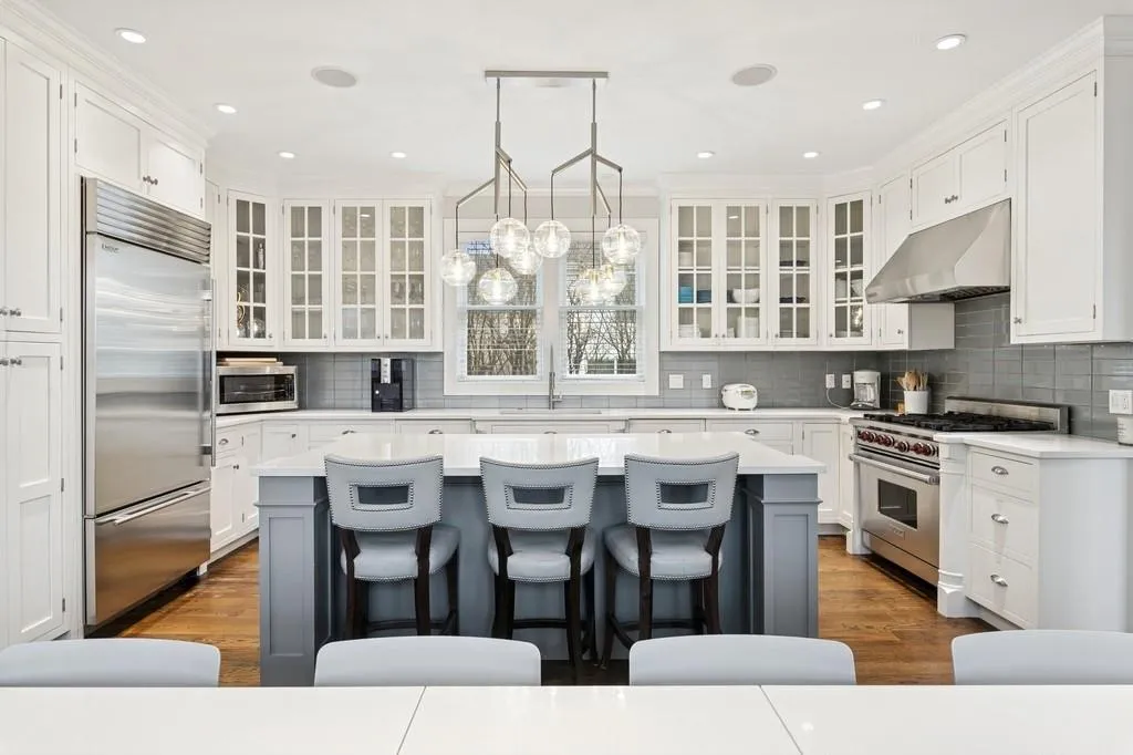 Kitchen featuring under cabinet range hood, white cabinetry, high quality appliances, and a kitchen bar Kitchen featuring under cabinet range hood, white cabinetry, high quality appliances, and a kitchen bar