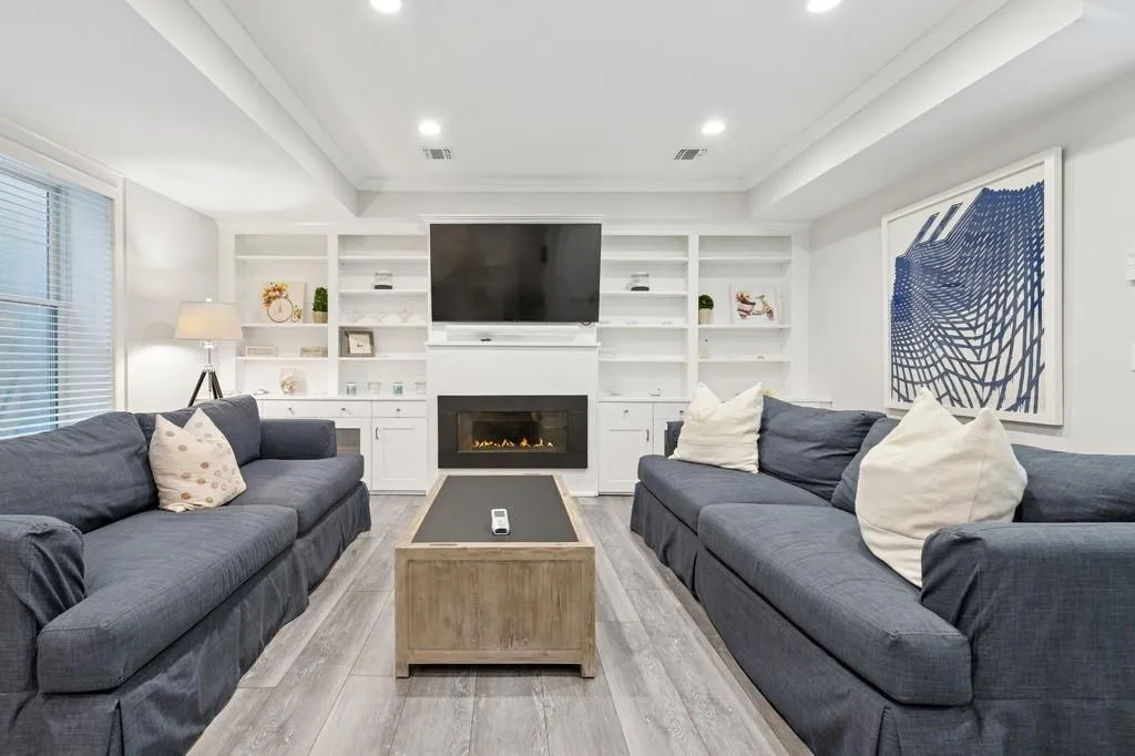Living area featuring visible vents, light wood finished floors, and a large fireplace Living area featuring visible vents, light wood finished floors, and a large fireplace