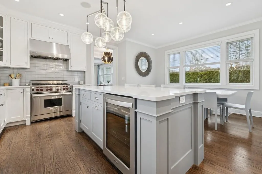 Kitchen featuring premium stove, dark wood-type flooring, wine cooler, under cabinet range hood, and crown molding Kitchen featuring premium stove, dark wood-type flooring, wine cooler, under cabinet range hood, and crown molding