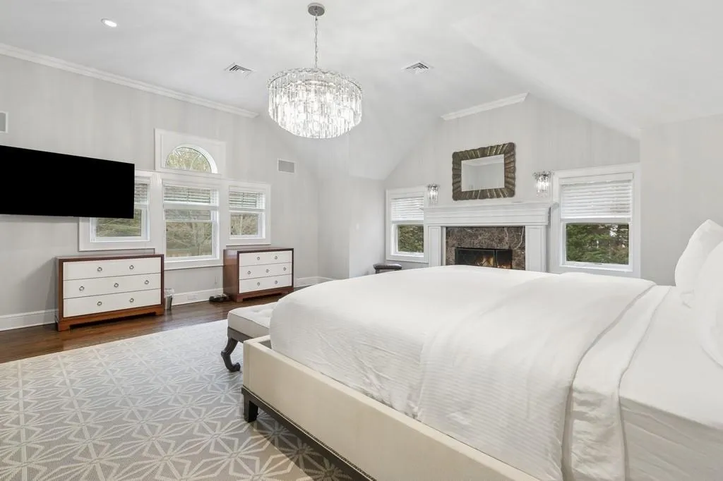 Bedroom featuring visible vents, wood finished floors, a high end fireplace, and vaulted ceiling Bedroom featuring visible vents, wood finished floors, a high end fireplace, and vaulted ceiling