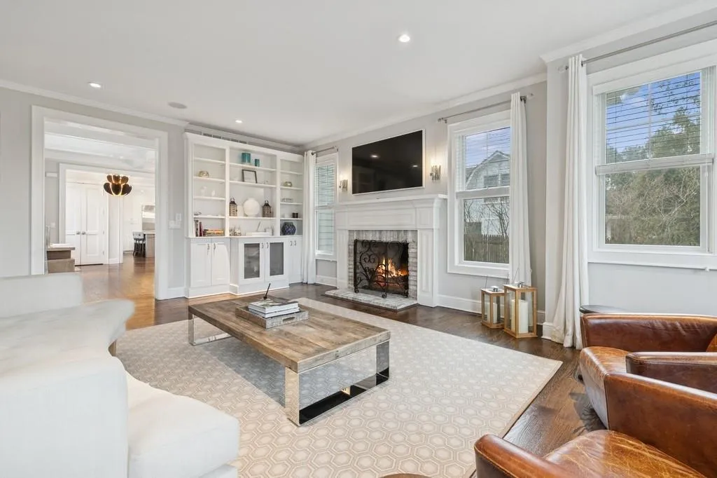 Living room with ornamental molding, wood finished floors, recessed lighting, baseboards, and a brick fireplace Living room with ornamental molding, wood finished floors, recessed lighting, baseboards, and a brick fireplace
