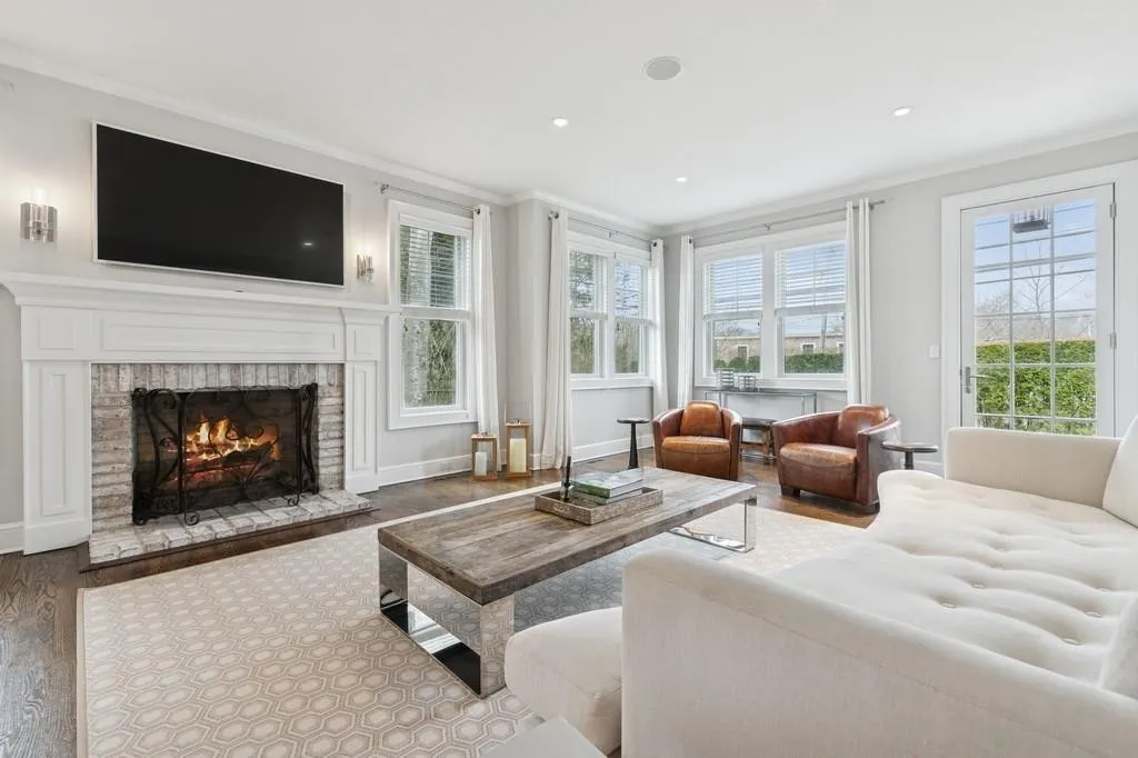 Living room with wood finished floors, a fireplace, baseboards, and ornamental molding Living room with wood finished floors, a fireplace, baseboards, and ornamental molding