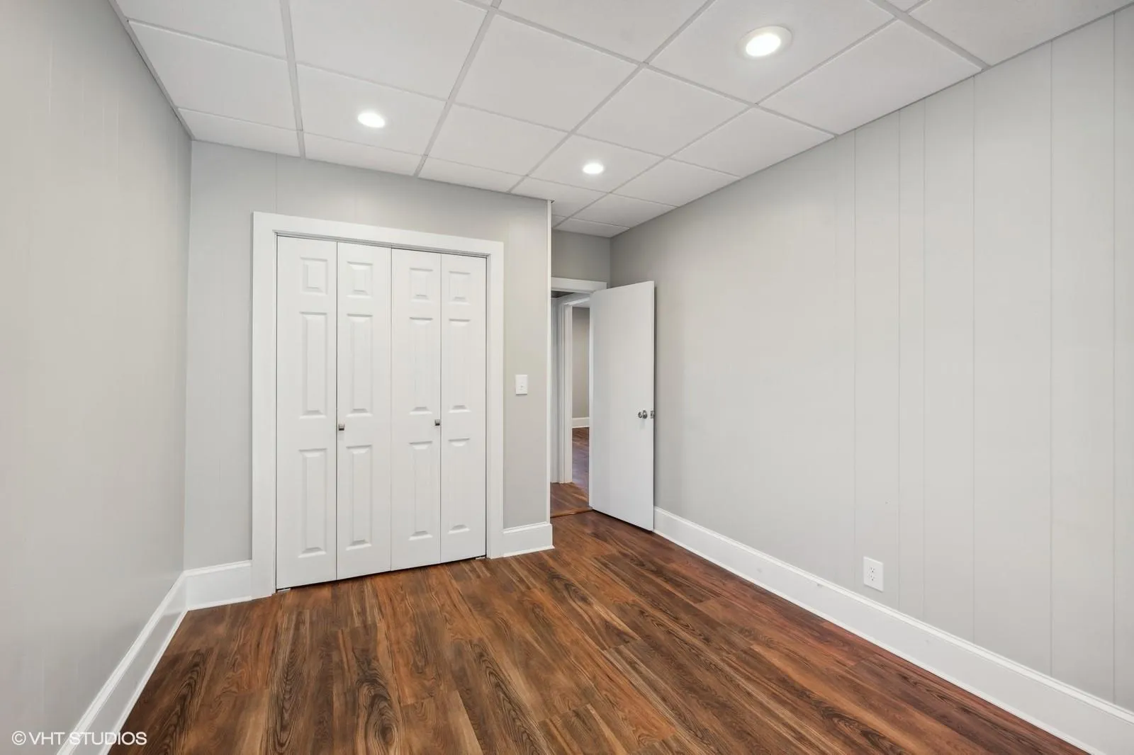 Unfurnished bedroom featuring a closet, baseboards, a paneled ceiling, and dark wood finished floors Unfurnished bedroom featuring a closet, baseboards, a paneled ceiling, and dark wood finished floors