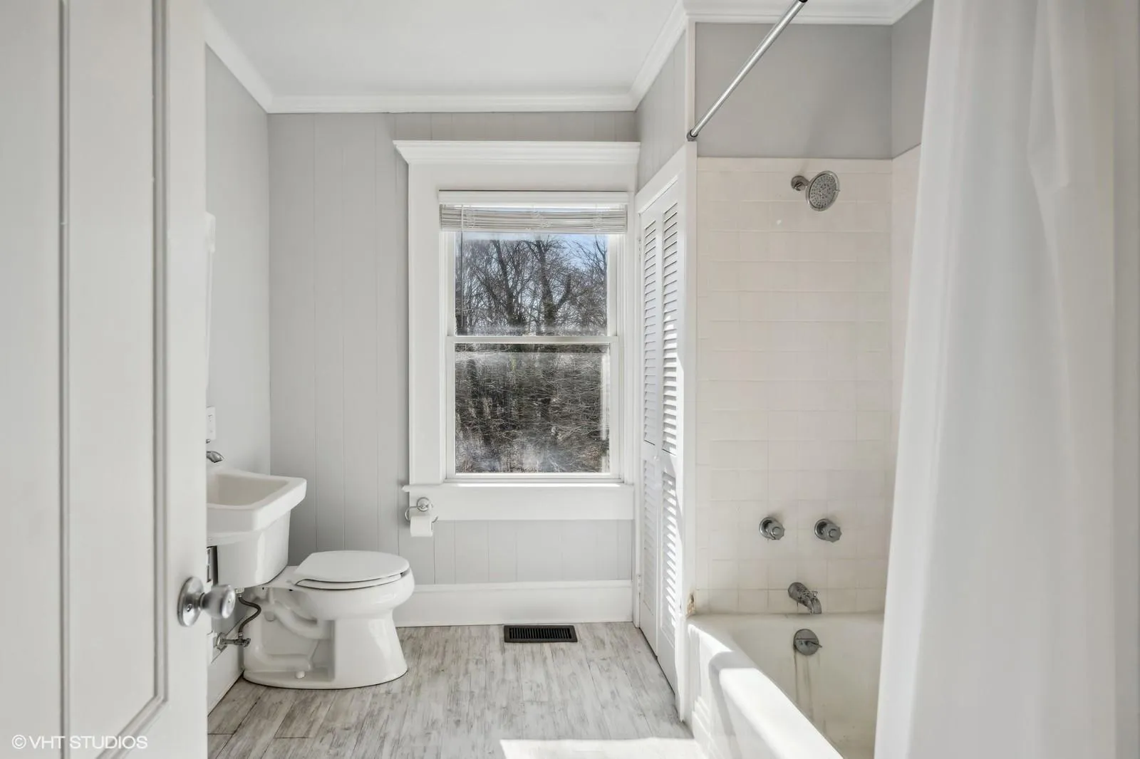 Full bathroom featuring toilet, crown molding, wood finished floors, and shower / tub combo with curtain Full bathroom featuring toilet, crown molding, wood finished floors, and shower / tub combo with curtain