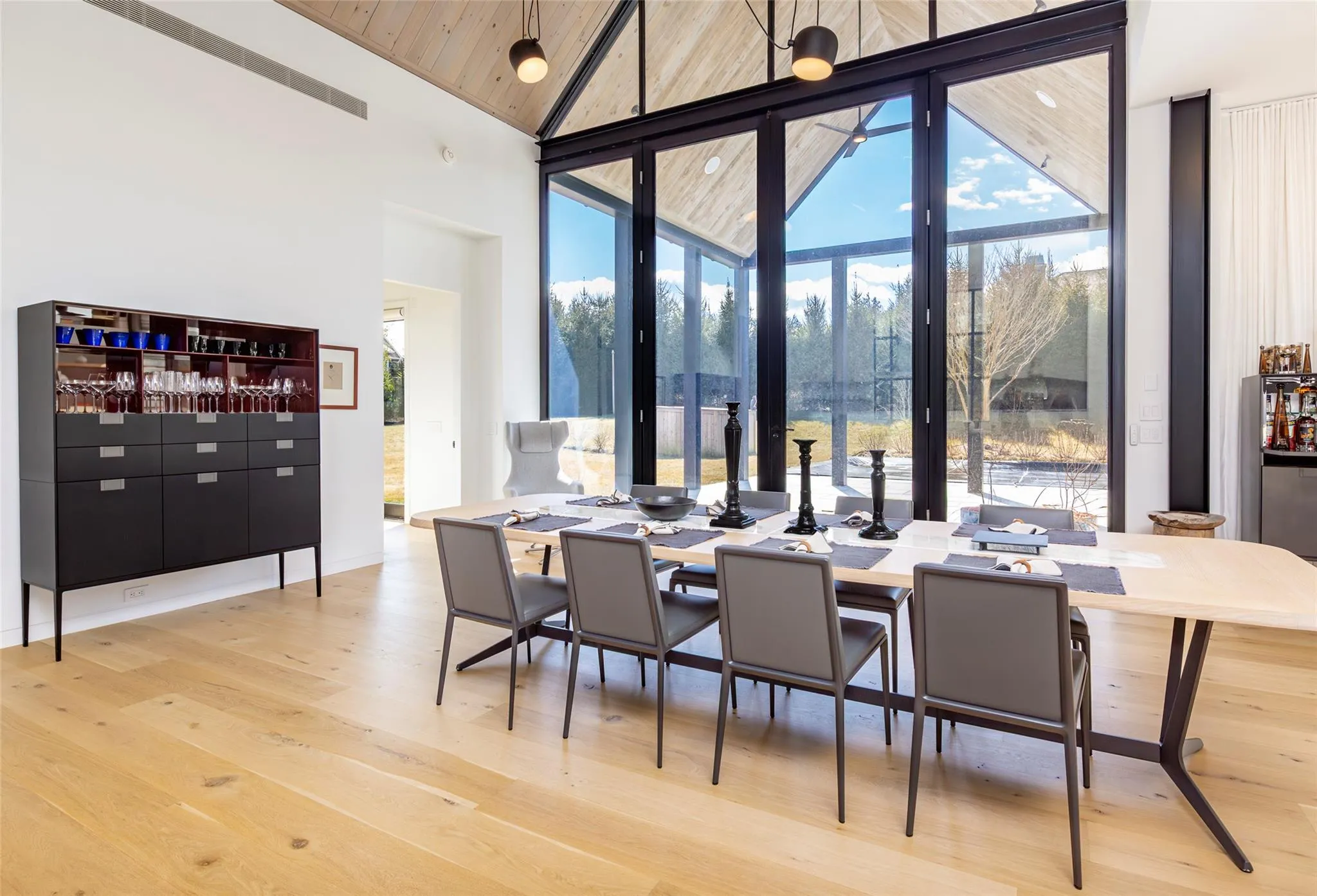 Dining space featuring a wall of windows, light wood-style flooring, plenty of natural light, and high vaulted ceiling Dining space featuring a wall of windows, light wood-style flooring, plenty of natural light, and high vaulted ceiling
