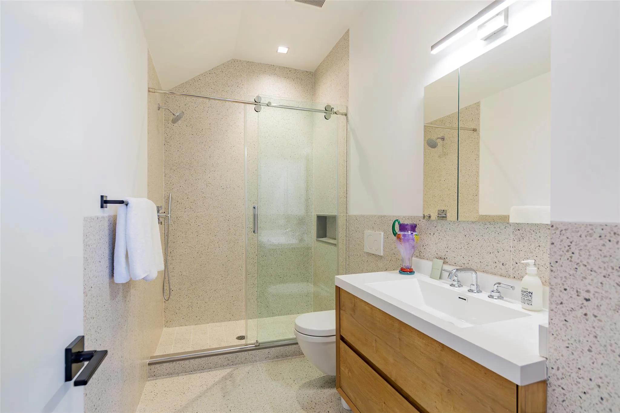 Bathroom featuring toilet, a stall shower, vanity, and vaulted ceiling Bathroom featuring toilet, a stall shower, vanity, and vaulted ceiling