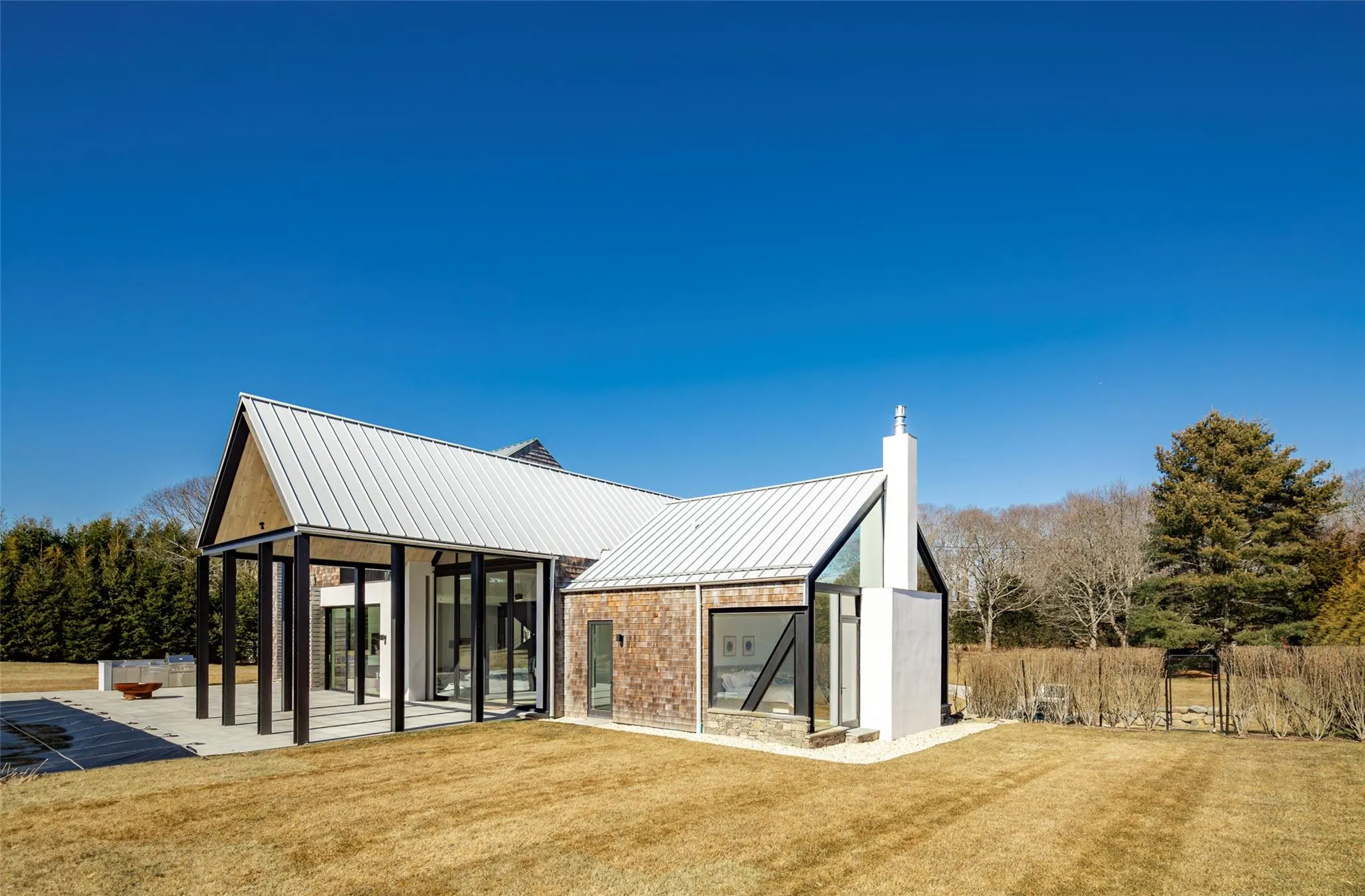 Rear view of property featuring metal roof, a patio, a lawn, and a standing seam roof Rear view of property featuring metal roof, a patio, a lawn, and a standing seam roof