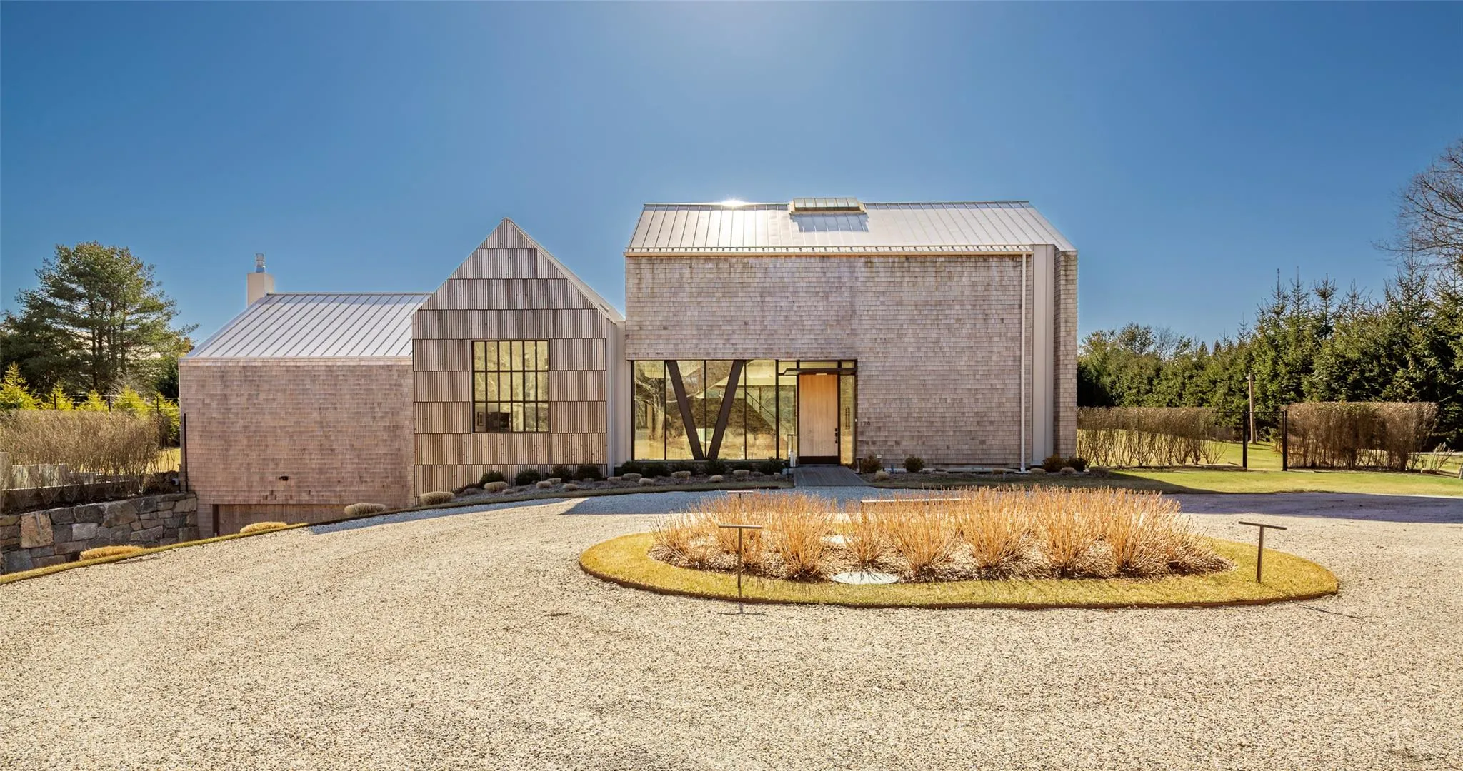 Back of property featuring brick siding, a chimney, driveway, and metal roof Back of property featuring brick siding, a chimney, driveway, and metal roof