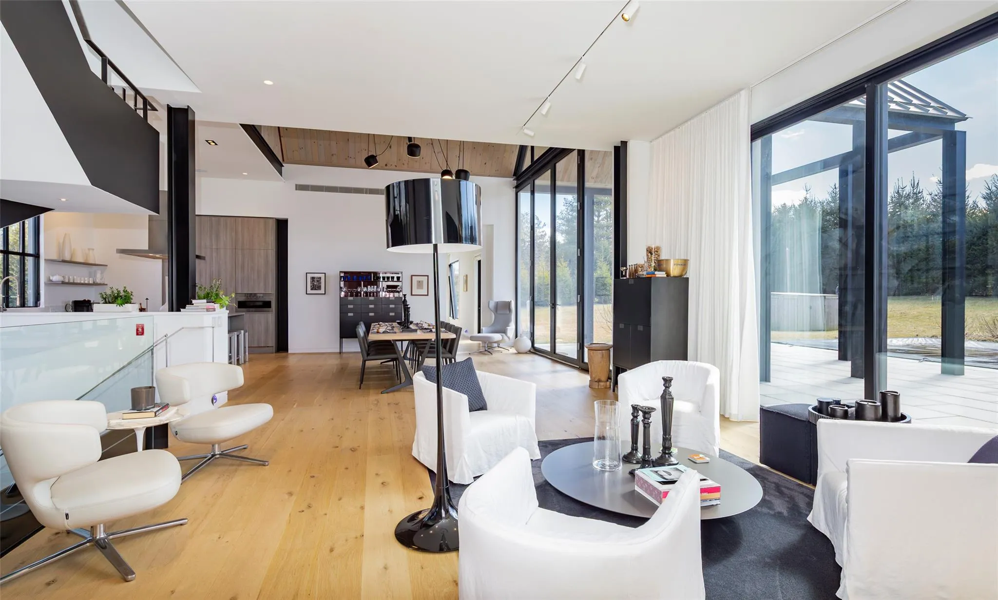 Living room featuring light wood finished floors, track lighting, and floor to ceiling windows Living room featuring light wood finished floors, track lighting, and floor to ceiling windows