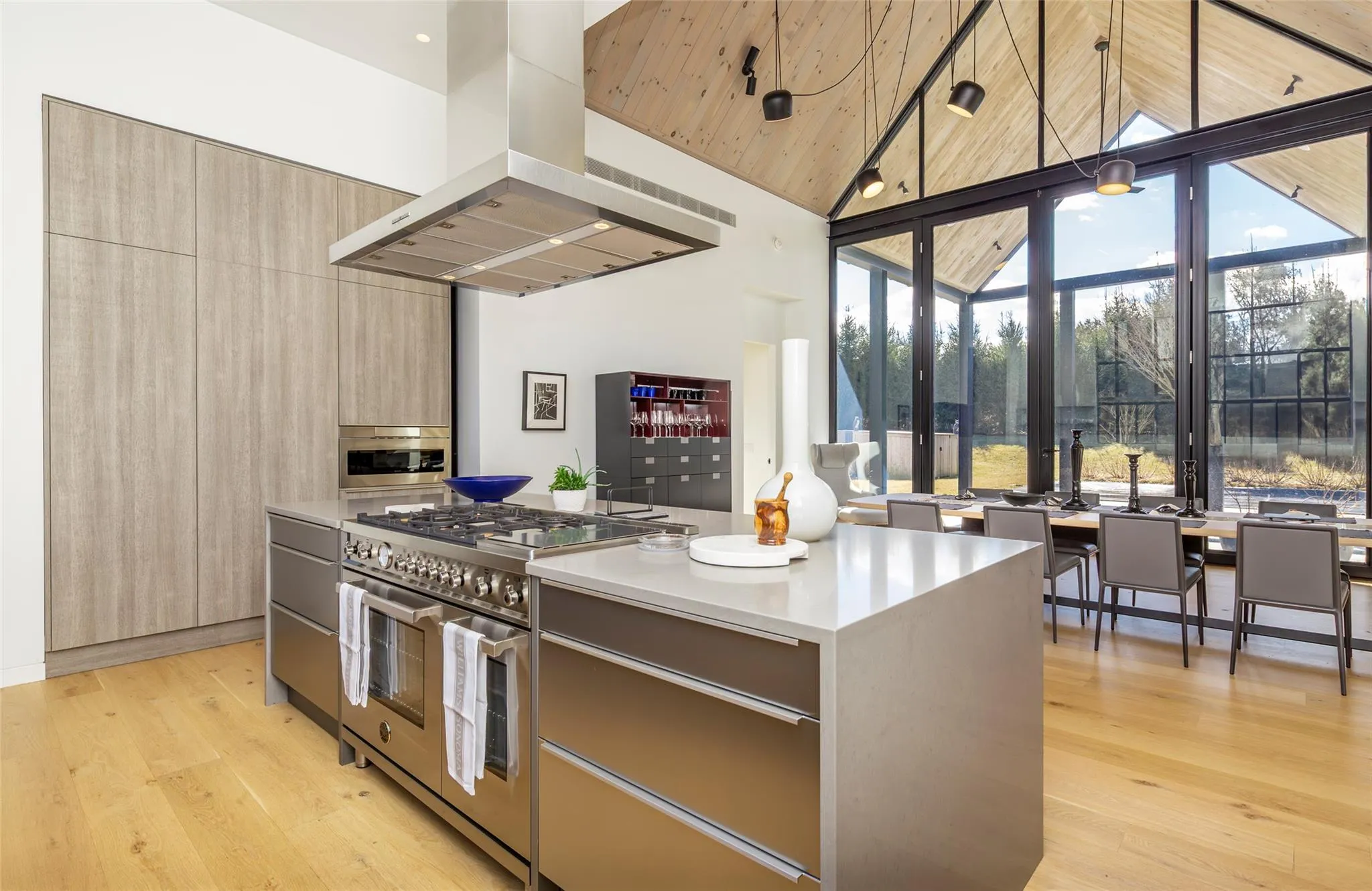 Kitchen with light wood-style flooring, modern cabinets, stainless steel stove, and island range hood Kitchen with light wood-style flooring, modern cabinets, stainless steel stove, and island range hood