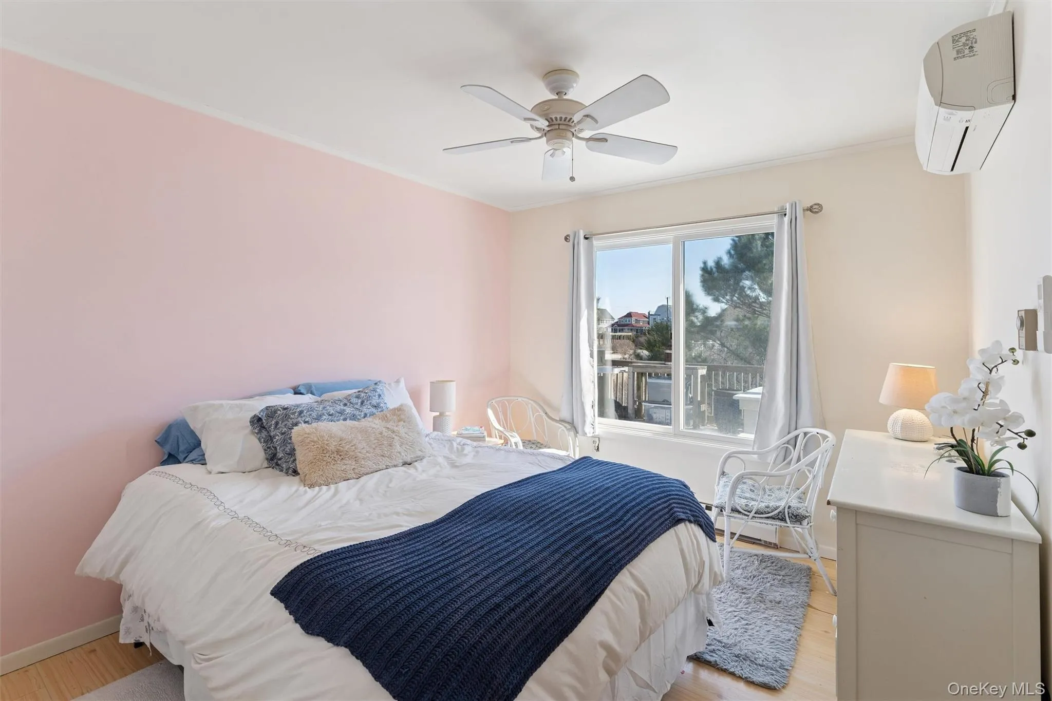 Bedroom featuring ceiling fan, baseboards, light wood finished floors, and a wall mounted AC Bedroom featuring ceiling fan, baseboards, light wood finished floors, and a wall mounted AC