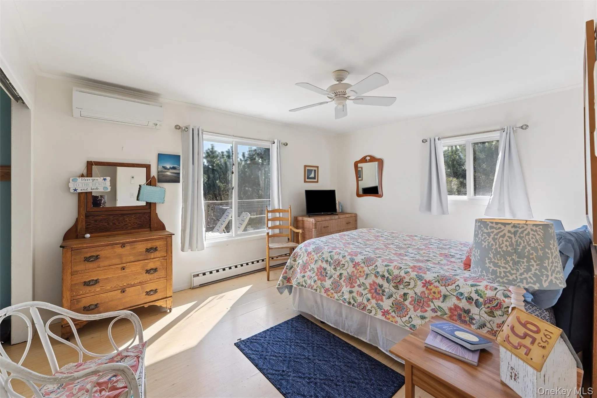 Bedroom featuring ornamental molding, wood finished floors, a wall mounted AC, a ceiling fan, and a baseboard radiator Bedroom featuring ornamental molding, wood finished floors, a wall mounted AC, a ceiling fan, and a baseboard radiator