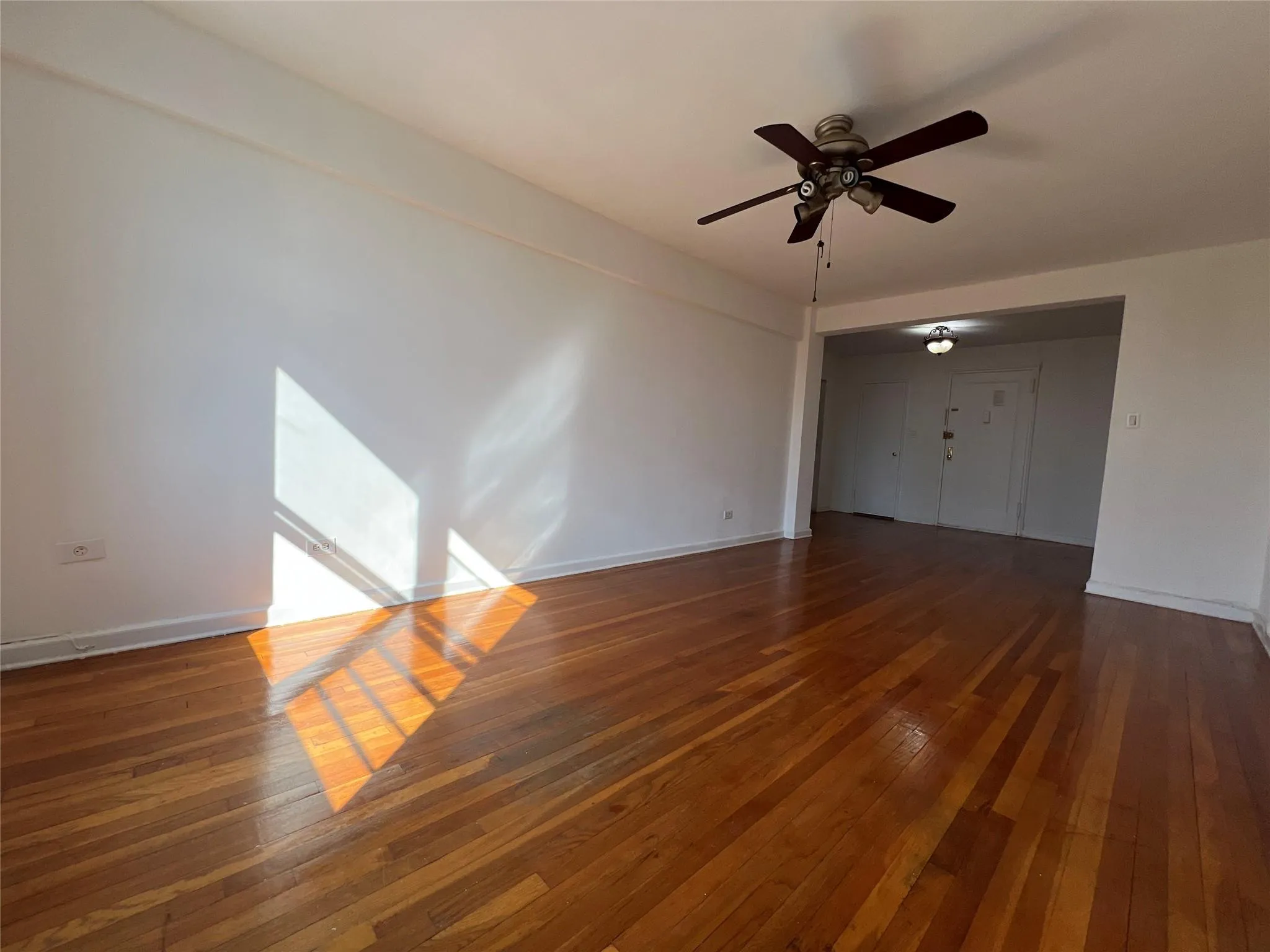 Unfurnished living room featuring ceiling fan, baseboards, and hardwood / wood-style flooring Unfurnished living room featuring ceiling fan, baseboards, and hardwood / wood-style flooring