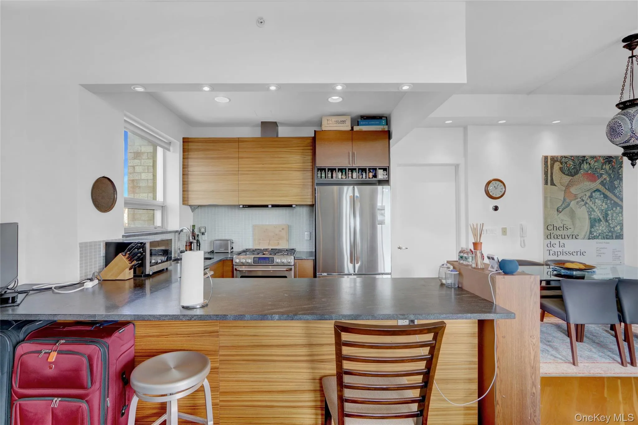 Kitchen with a peninsula, a toaster, stainless steel appliances, decorative backsplash, and dark countertops Kitchen with a peninsula, a toaster, stainless steel appliances, decorative backsplash, and dark countertops