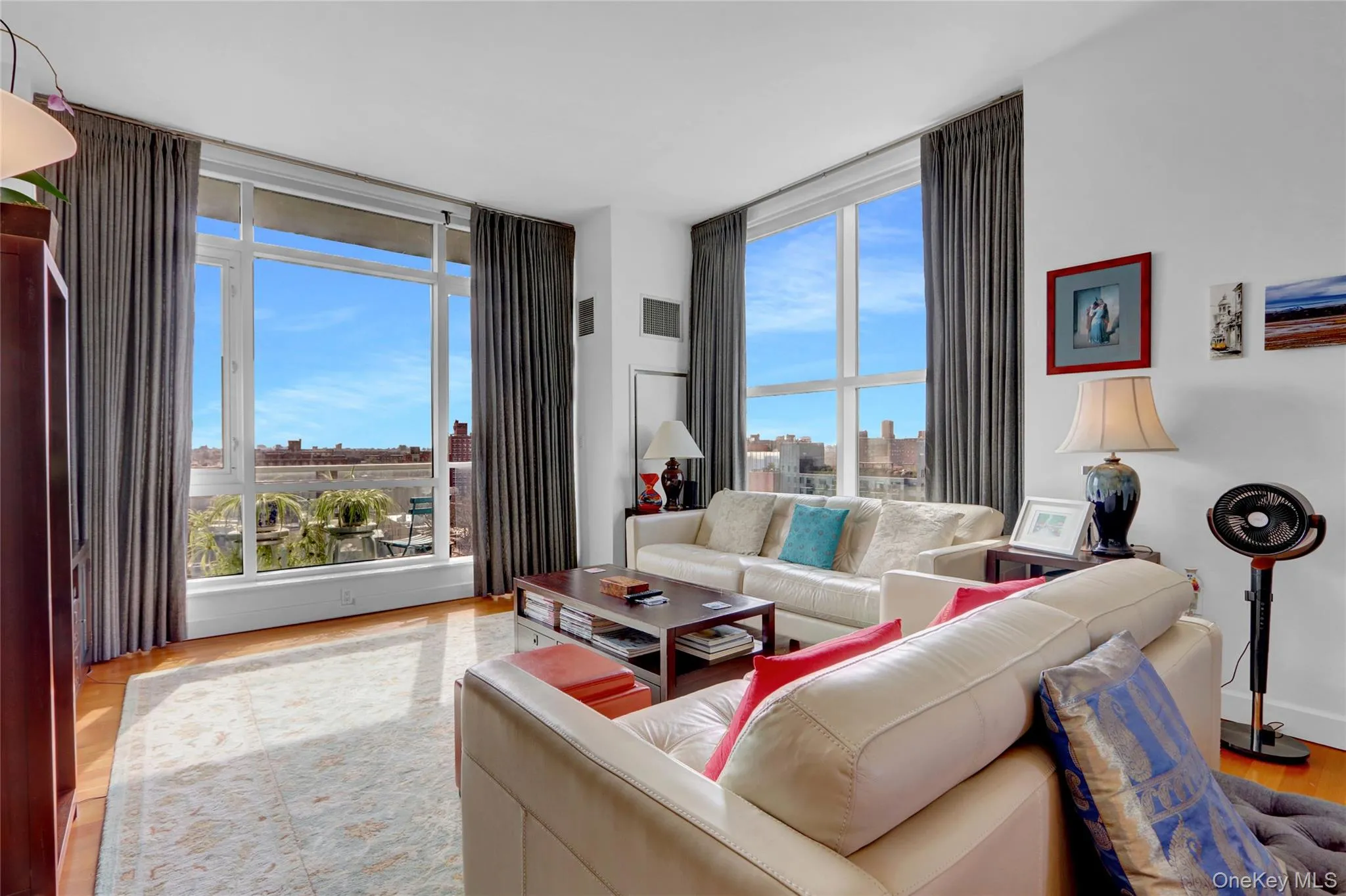 Living room with a city view, floor to ceiling windows, wood finished floors, and visible vents Living room with a city view, floor to ceiling windows, wood finished floors, and visible vents