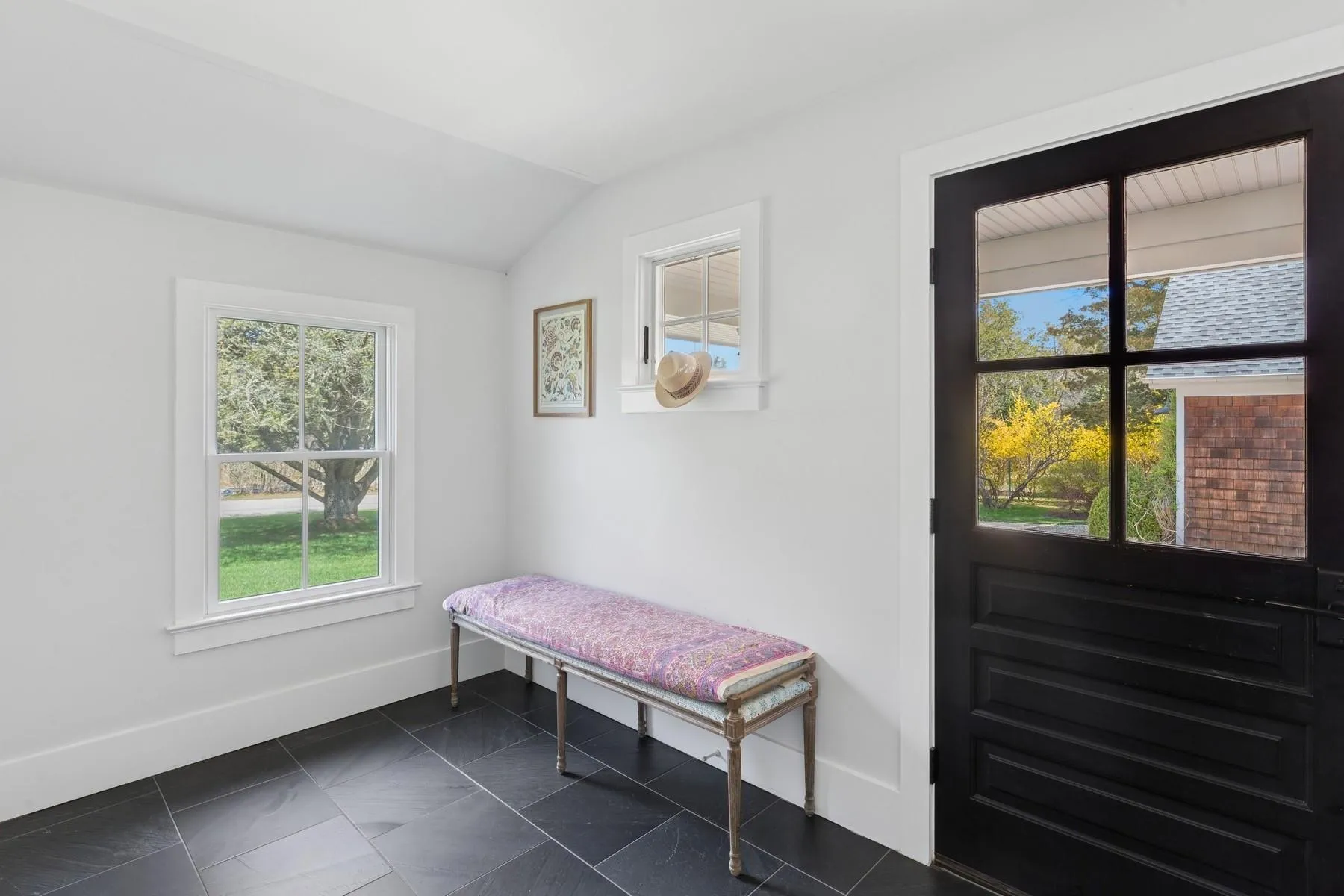 Doorway to outside featuring lofted ceiling and baseboards Doorway to outside featuring lofted ceiling and baseboards