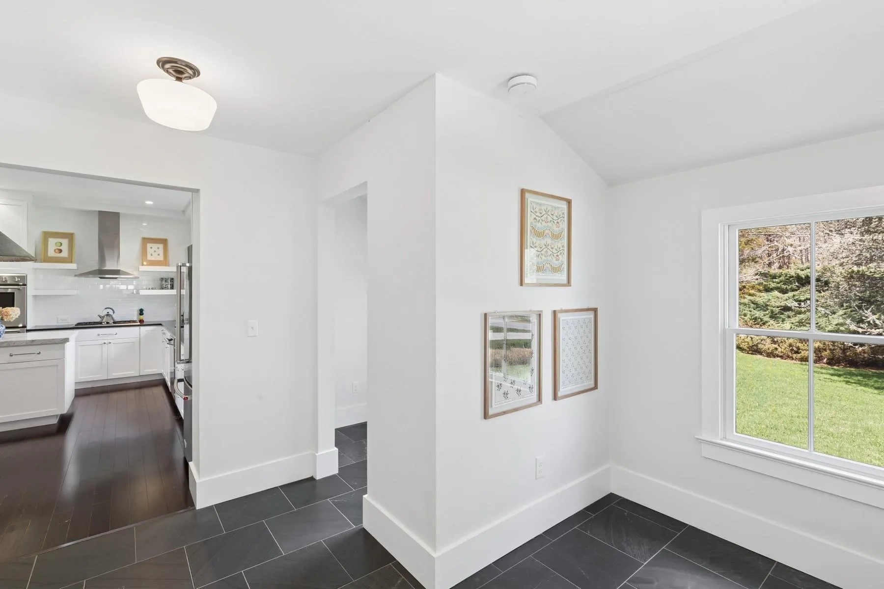 Unfurnished dining area featuring lofted ceiling, dark tile patterned flooring, and baseboards Unfurnished dining area featuring lofted ceiling, dark tile patterned flooring, and baseboards
