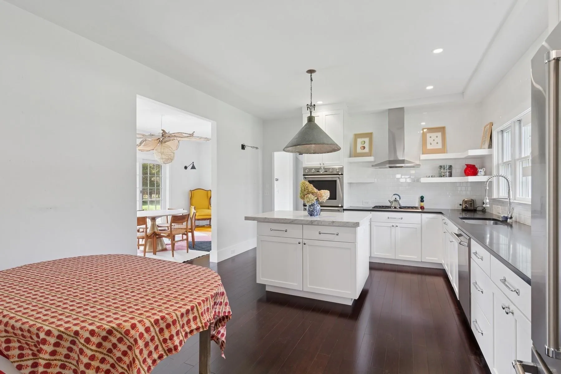 Kitchen featuring a sink, white cabinetry, backsplash, wall chimney range hood, and appliances with stainless steel finishes Kitchen featuring a sink, white cabinetry, backsplash, wall chimney range hood, and appliances with stainless steel finishes