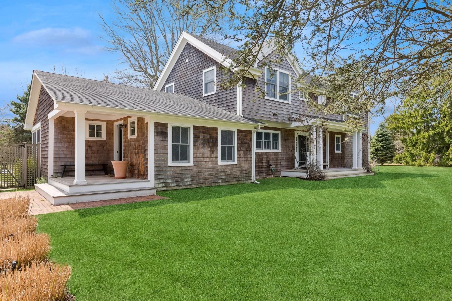 Rear view of house featuring a porch, a lawn, and a shingled roof Rear view of house featuring a porch, a lawn, and a shingled roof