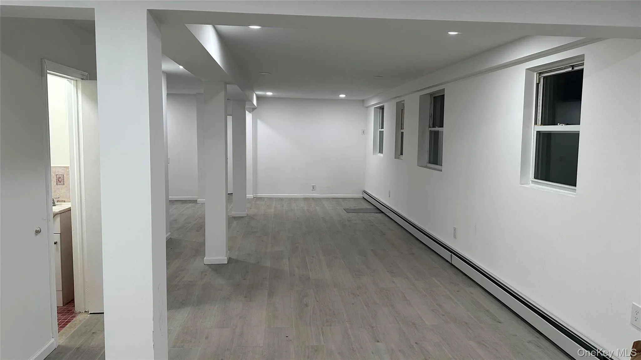 Corridor with a baseboard heating unit, light wood-style flooring, and recessed lighting Corridor with a baseboard heating unit, light wood-style flooring, and recessed lighting