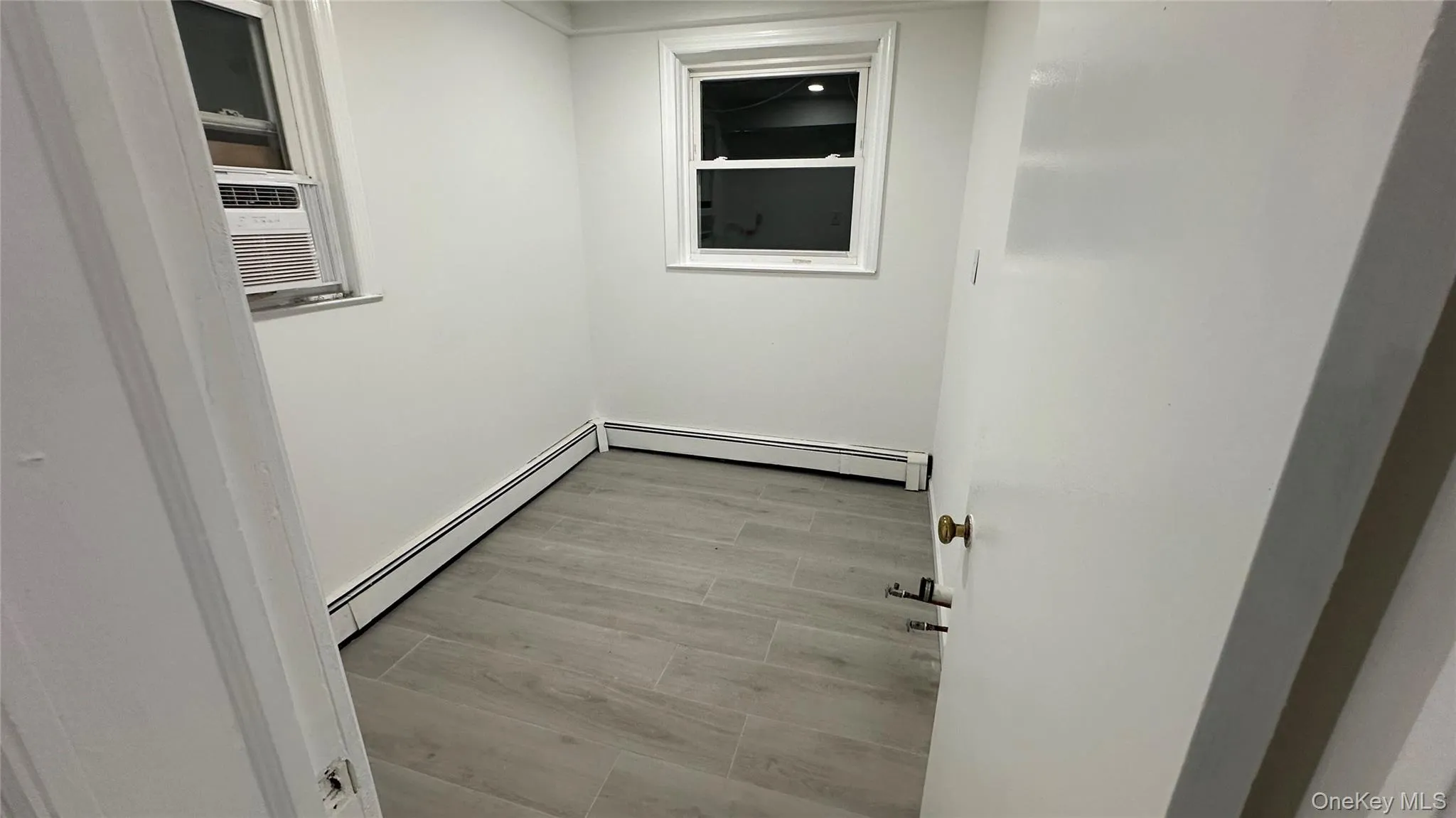 Hall featuring light wood finished floors and baseboard heating Hall featuring light wood finished floors and baseboard heating