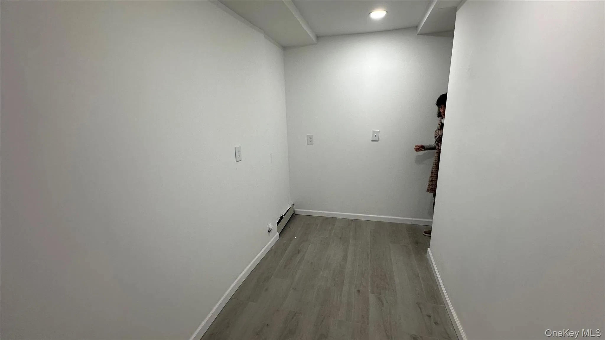 Laundry area featuring light wood finished floors, a baseboard radiator, and recessed lighting Laundry area featuring light wood finished floors, a baseboard radiator, and recessed lighting