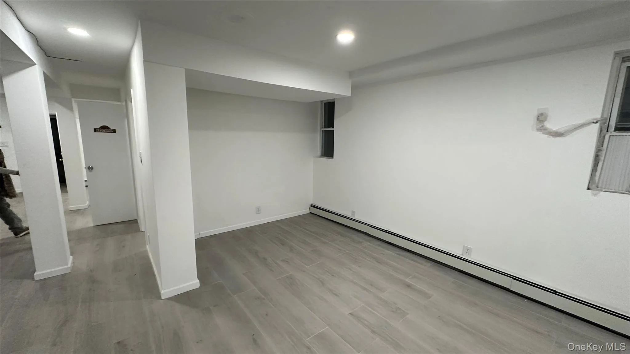 Finished below grade area featuring a baseboard radiator and light wood-type flooring Finished below grade area featuring a baseboard radiator and light wood-type flooring