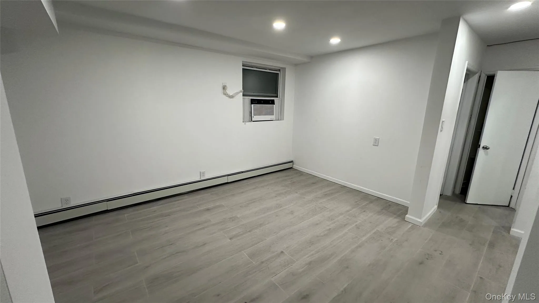 Finished below grade area featuring a baseboard heating unit, light wood-type flooring, and recessed lighting Finished below grade area featuring a baseboard heating unit, light wood-type flooring, and recessed lighting