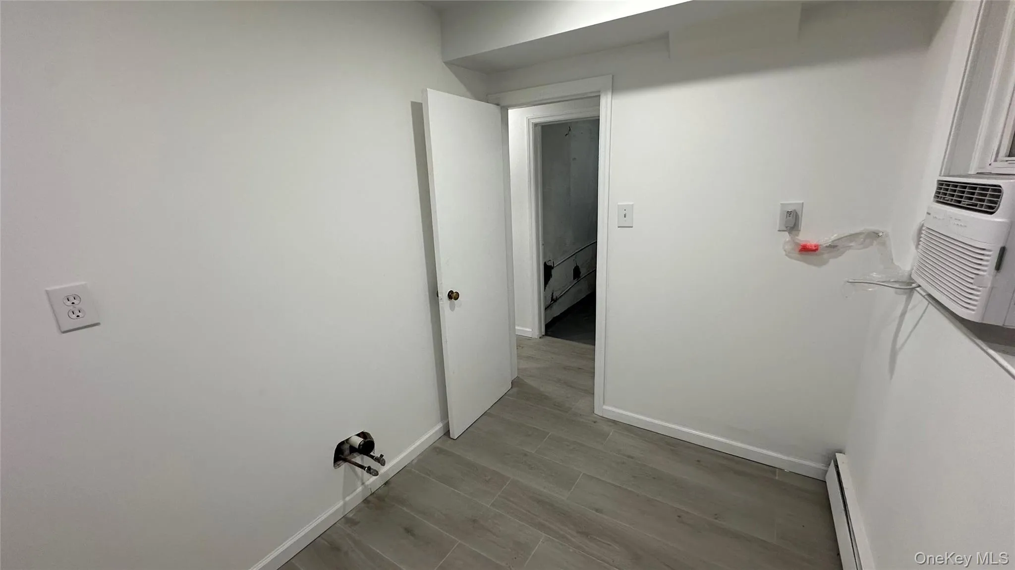 Hallway with wood finish floors, a baseboard heating unit, and cooling unit Hallway with wood finish floors, a baseboard heating unit, and cooling unit