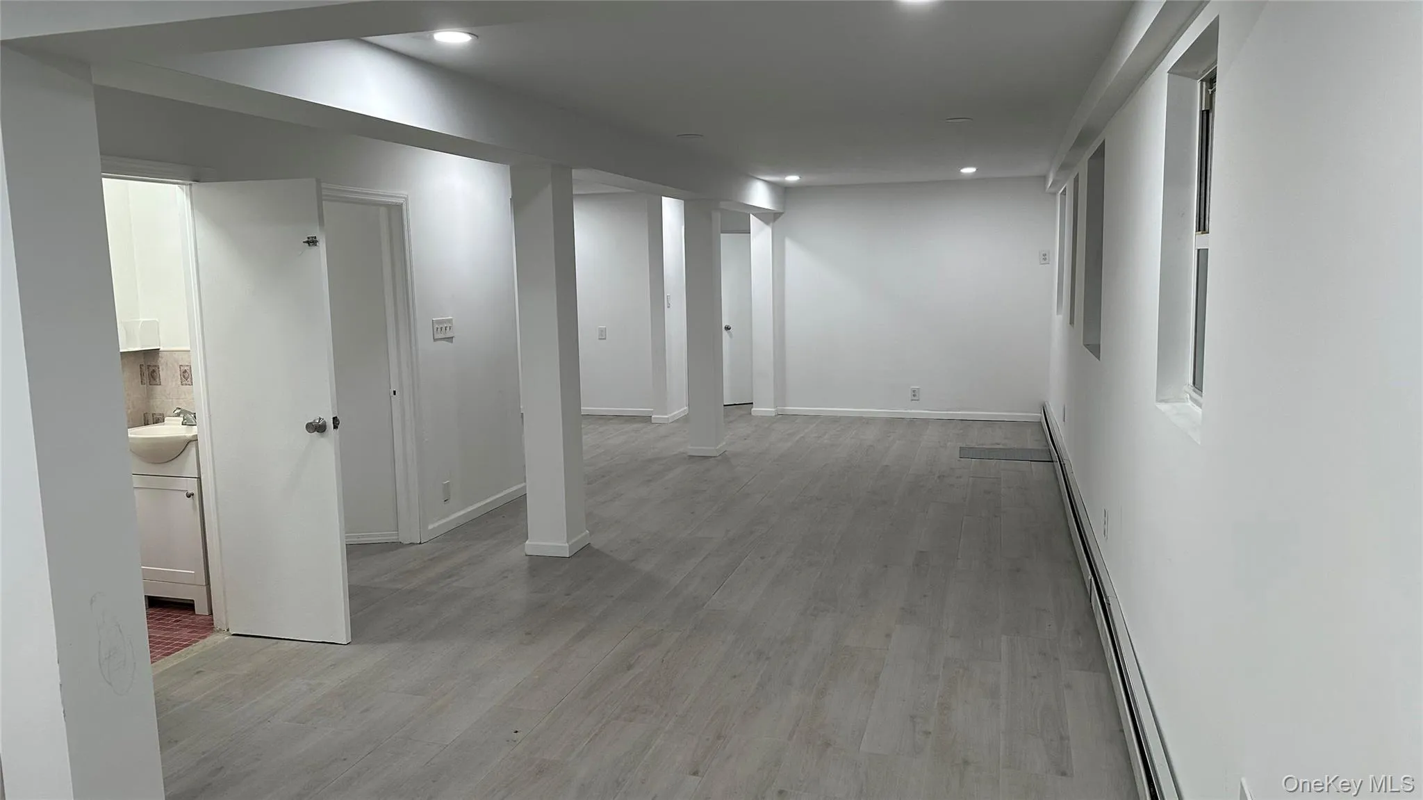Corridor with a baseboard radiator, light wood finished floors, and recessed lighting Corridor with a baseboard radiator, light wood finished floors, and recessed lighting