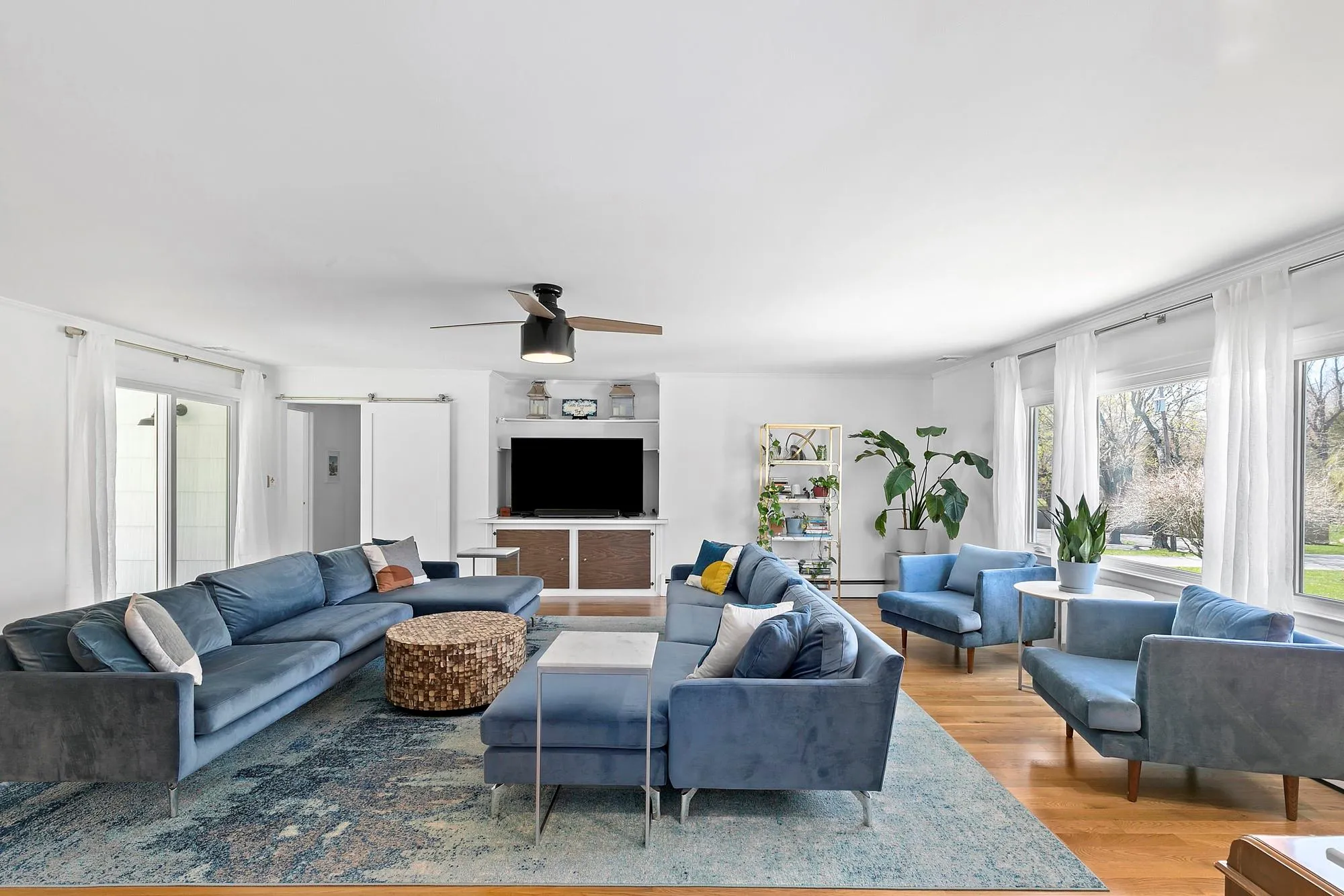 Living room with ceiling fan, a barn door, and wood finished floors Living room with ceiling fan, a barn door, and wood finished floors