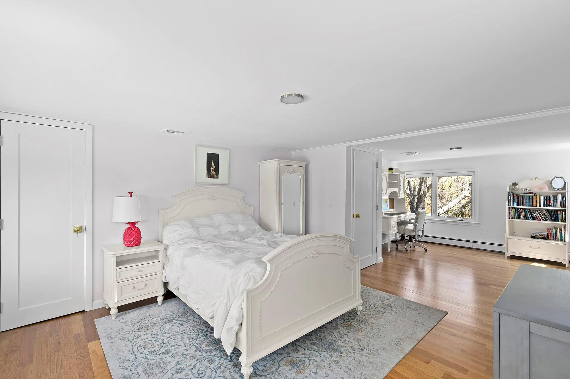 Bedroom featuring visible vents, light wood-style flooring, and a baseboard heating unit Bedroom featuring visible vents, light wood-style flooring, and a baseboard heating unit