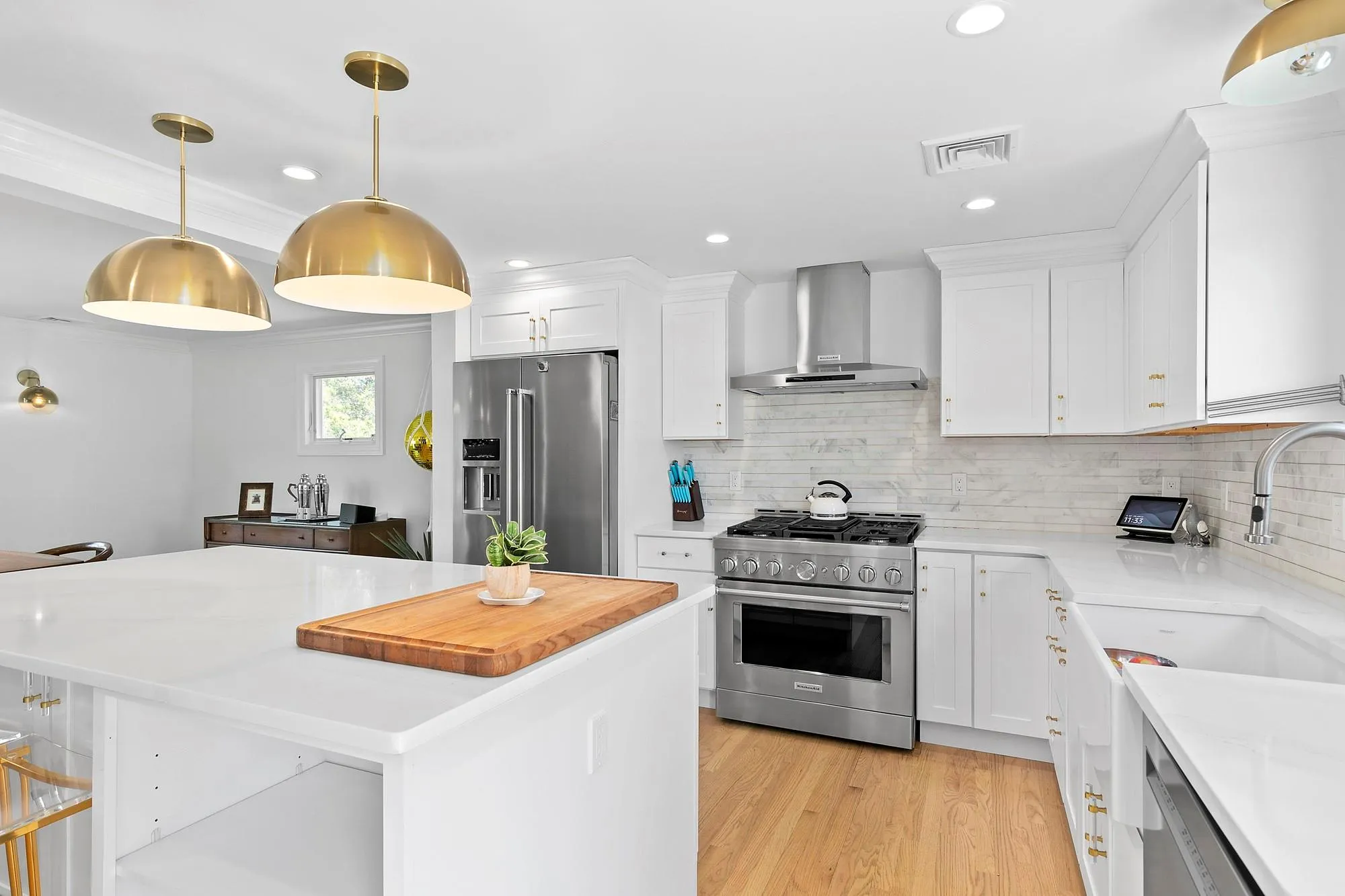 Kitchen featuring light wood-type flooring, visible vents, white cabinetry, wall chimney exhaust hood, and high end appliances Kitchen featuring light wood-type flooring, visible vents, white cabinetry, wall chimney exhaust hood, and high end appliances