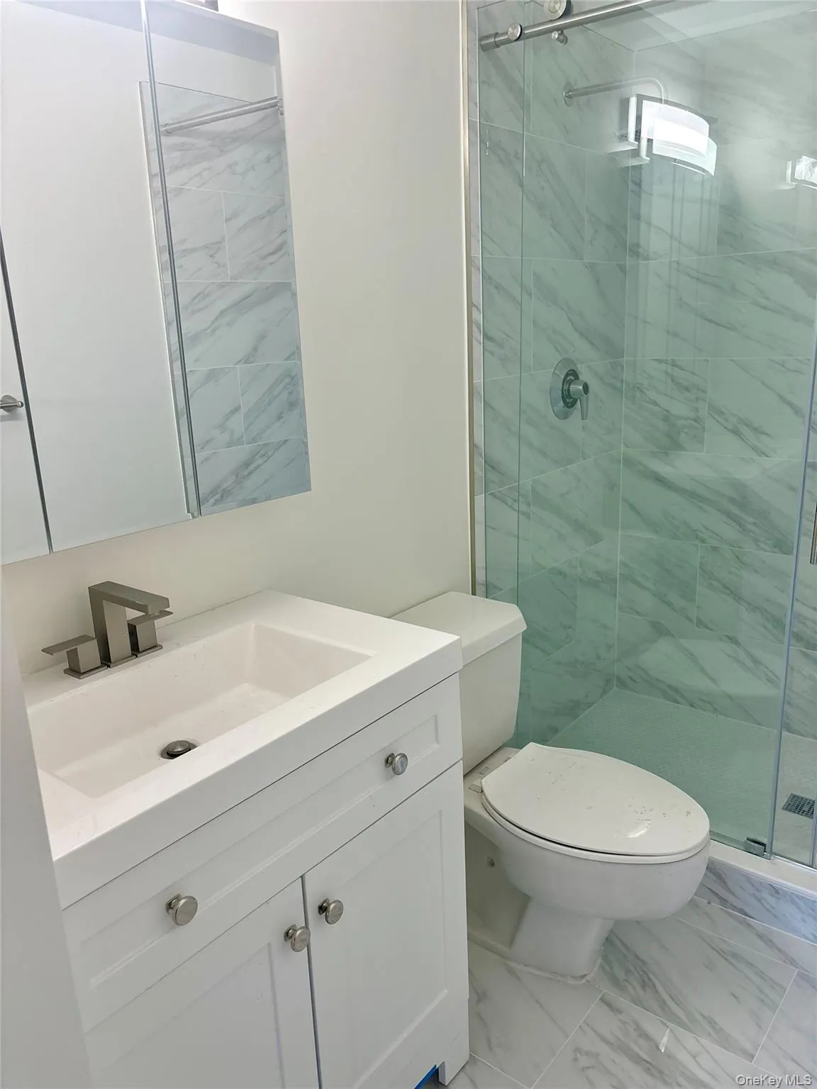 Bathroom featuring vanity, a stall shower, and marble finish floors Bathroom featuring vanity, a stall shower, and marble finish floors