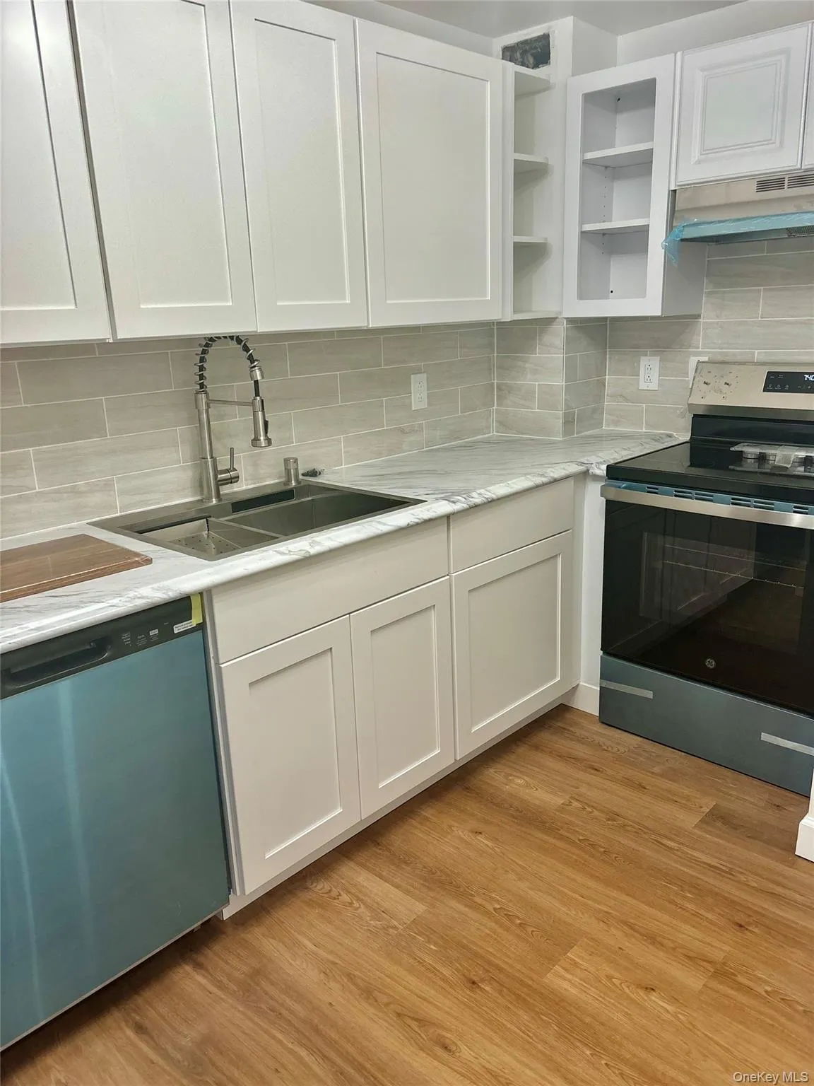 Kitchen featuring electric stove, dishwashing machine, under cabinet range hood, and white cabinets Kitchen featuring electric stove, dishwashing machine, under cabinet range hood, and white cabinets