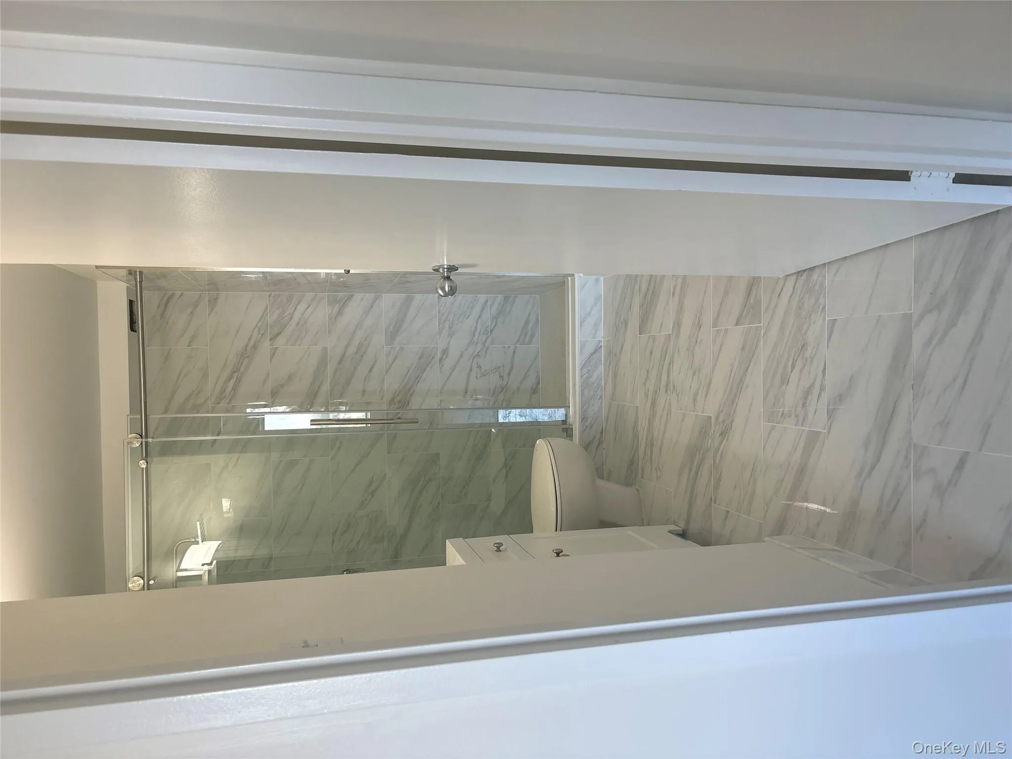 Full bathroom featuring a shower stall, vanity, and marble look tile flooring Full bathroom featuring a shower stall, vanity, and marble look tile flooring