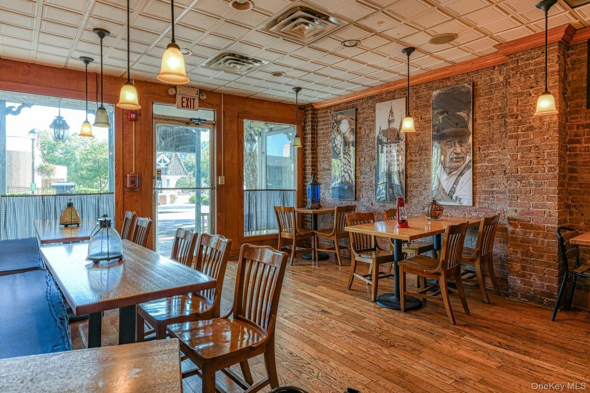 Dining area with visible vents, an ornate ceiling, brick wall, and wood-type flooring Dining area with visible vents, an ornate ceiling, brick wall, and wood-type flooring