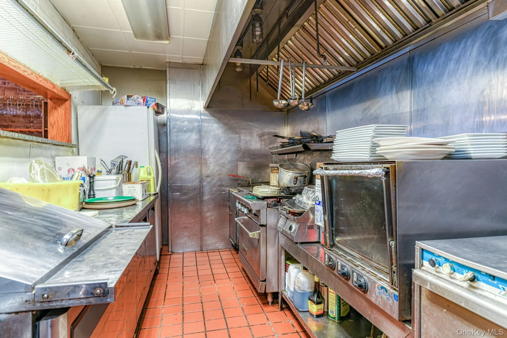 Kitchen featuring range with two ovens, stainless steel countertops, a paneled ceiling, and tile patterned flooring Kitchen featuring range with two ovens, stainless steel countertops, a paneled ceiling, and tile patterned flooring