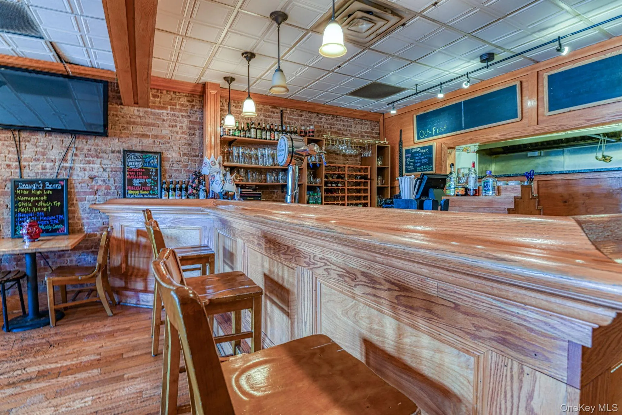 Bar featuring wood finished floors, an ornate ceiling, brick wall, and a dry bar Bar featuring wood finished floors, an ornate ceiling, brick wall, and a dry bar