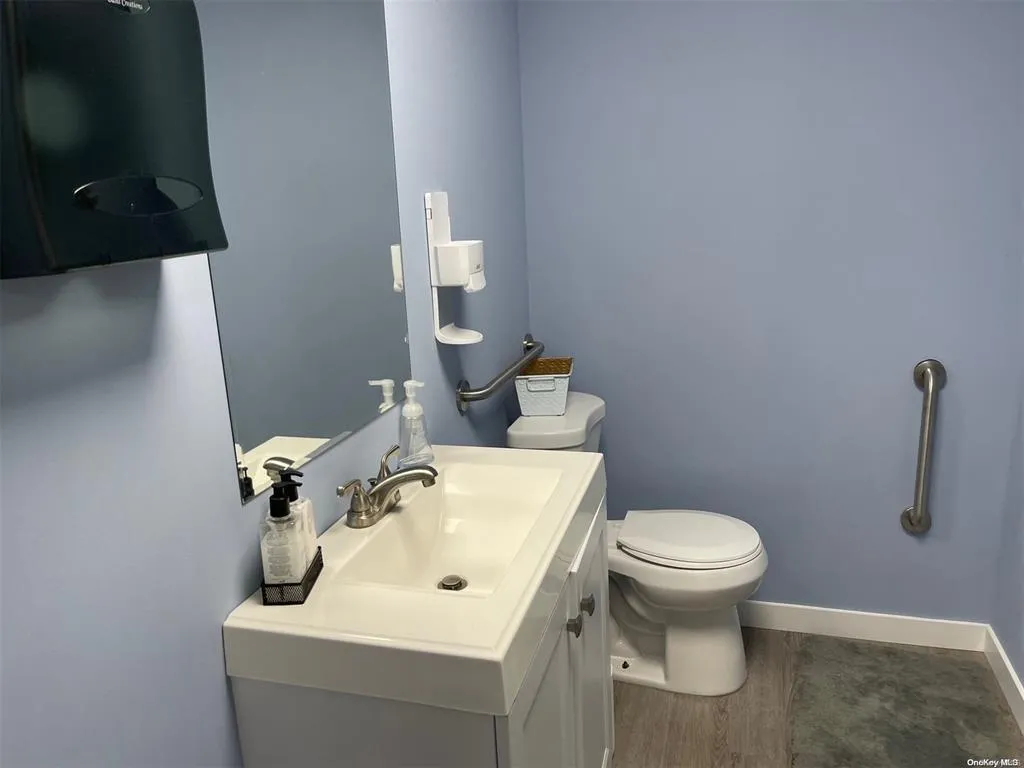 Half bathroom featuring baseboards, toilet, wood finished floors, and vanity Half bathroom featuring baseboards, toilet, wood finished floors, and vanity