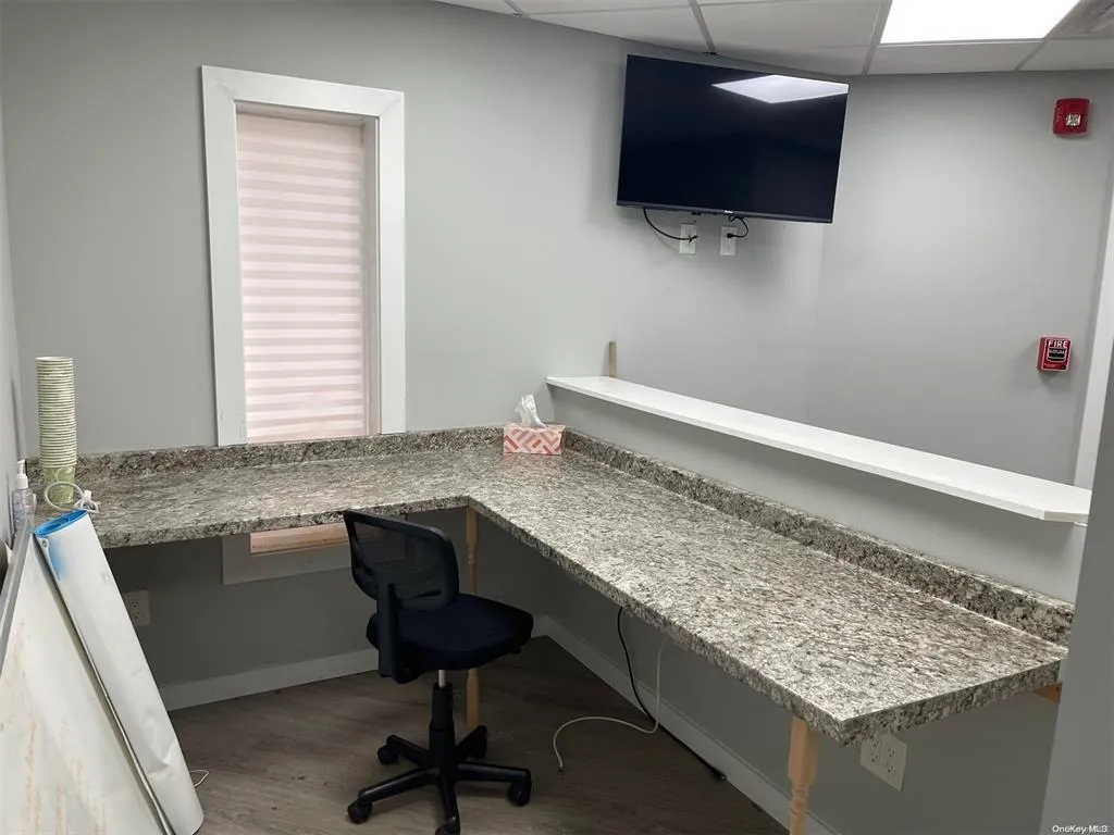 Office space with wood finished floors, baseboards, a drop ceiling, and built in study area Office space with wood finished floors, baseboards, a drop ceiling, and built in study area