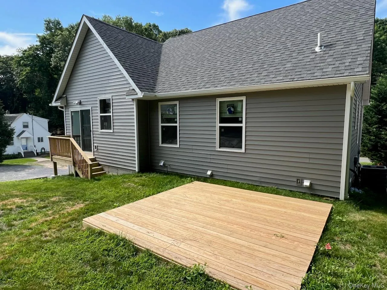 Back of house featuring roof with shingles, a yard, and a deck Back of house featuring roof with shingles, a yard, and a deck