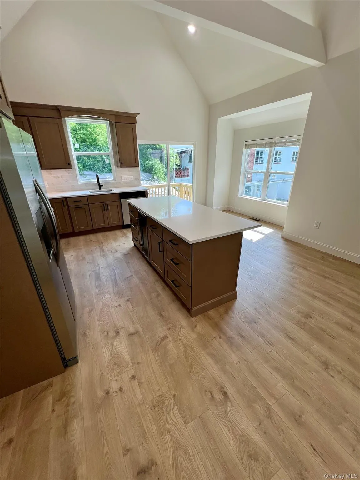 Kitchen with light countertops, light wood-style floors, high vaulted ceiling, tasteful backsplash, and healthy amount of natural light Kitchen with light countertops, light wood-style floors, high vaulted ceiling, tasteful backsplash, and healthy amount of natural light