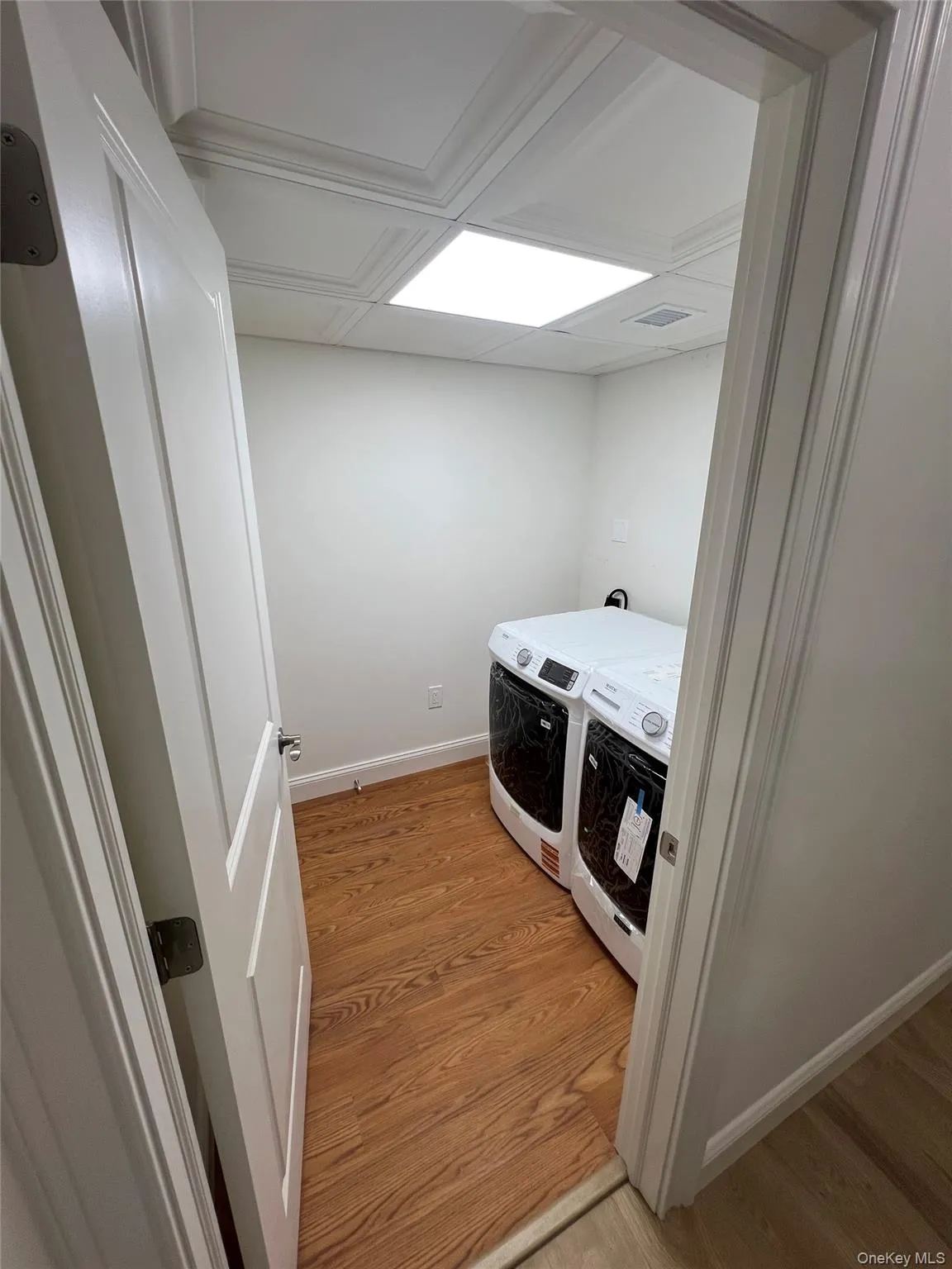 Washroom with washer and clothes dryer and light wood-style floors Washroom with washer and clothes dryer and light wood-style floors