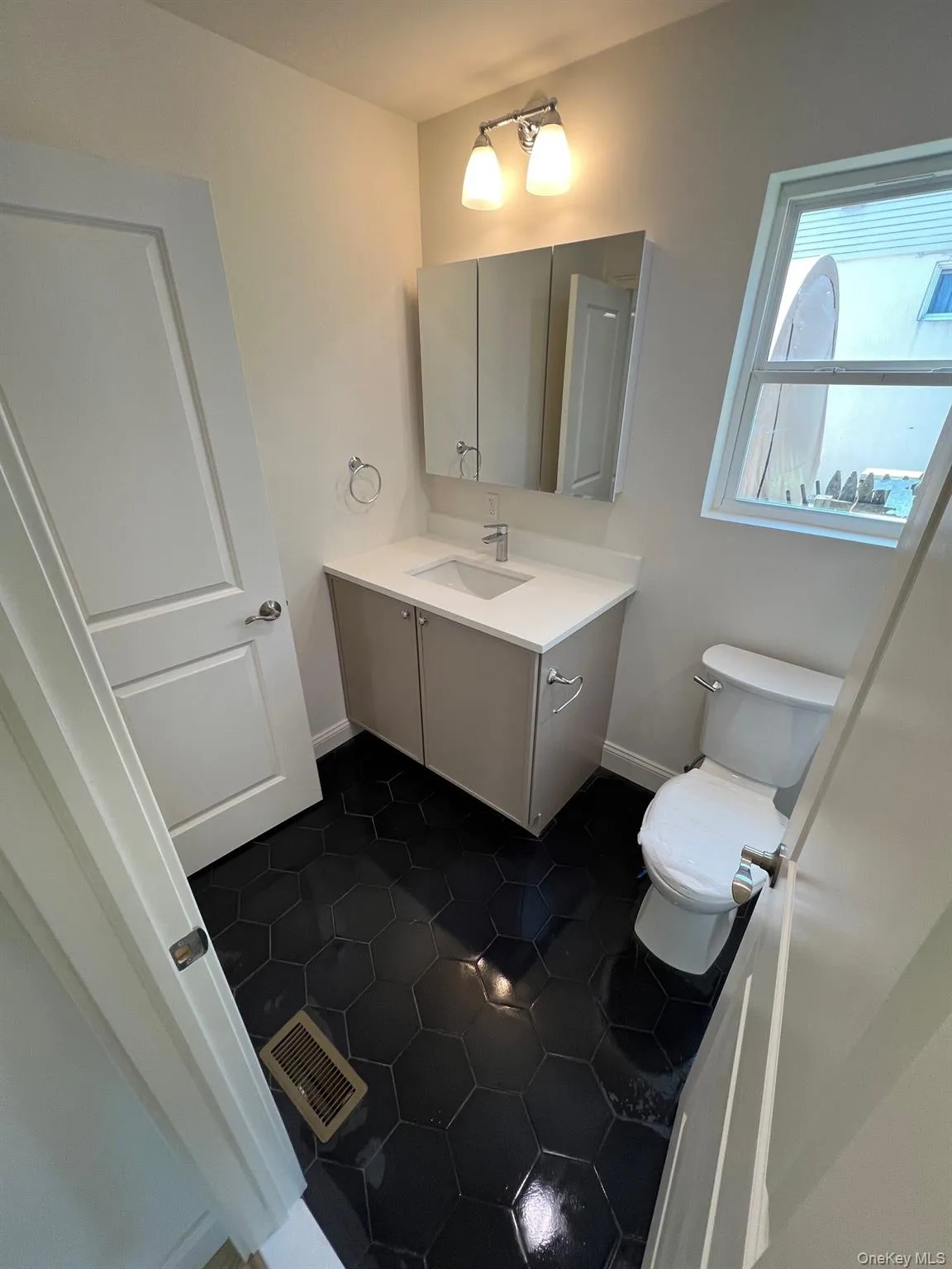 Half bath featuring visible vents, baseboards, toilet, vanity, and tile patterned flooring Half bath featuring visible vents, baseboards, toilet, vanity, and tile patterned flooring